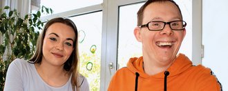 Eine Junge Frau malt mit einem Mann ein Bild mit bunten Farben